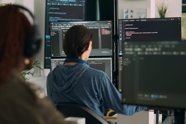 Database programer writing code on terminal window using multiple monitors in it agency office. System software developer typing database information, computing big data script.